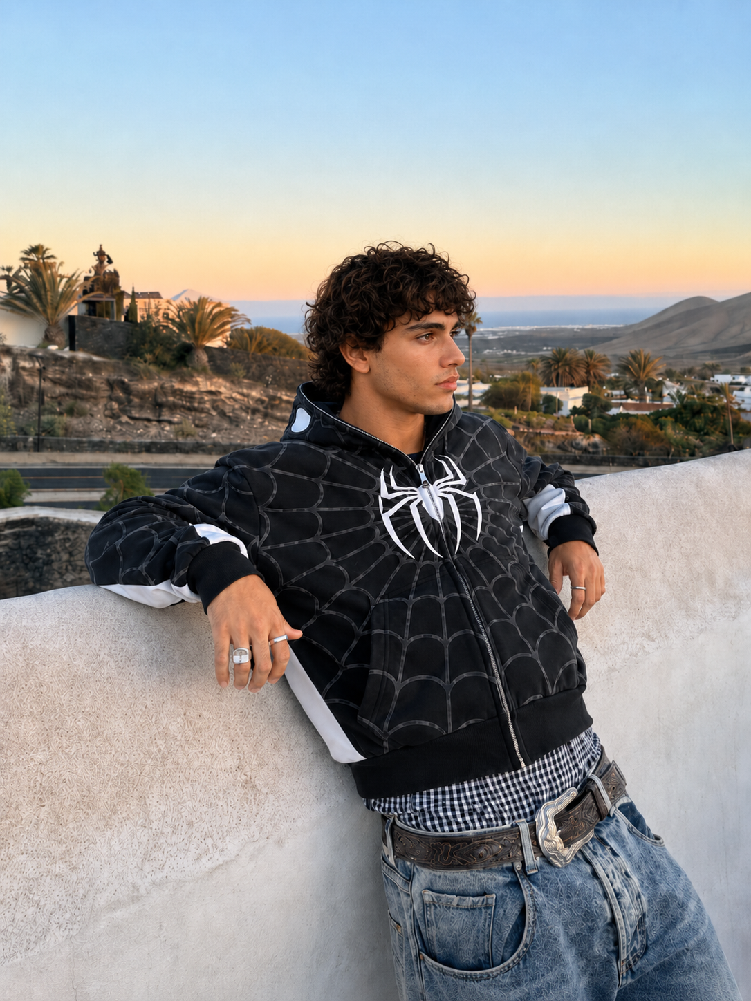 Nostalgic Misfits Noir Zip black white spidey hoodie male model leaning on wall sunset view palm trees Lanzarote editorial lifestyle shot