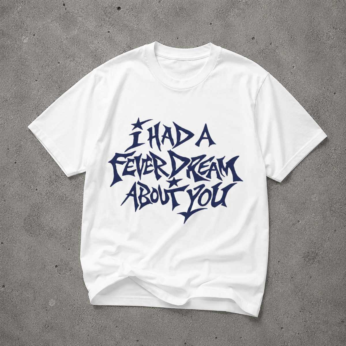 White unisex t-shirt with navy "I Had a Fever Dream About You" hand-lettered graphic print, flat lay on concrete background